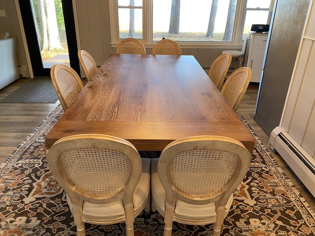 dining space with wood finished floors and a baseboard radiator