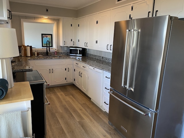 kitchen with dark wood-type flooring, ornamental molding, appliances with stainless steel finishes, white cabinetry, and a sink