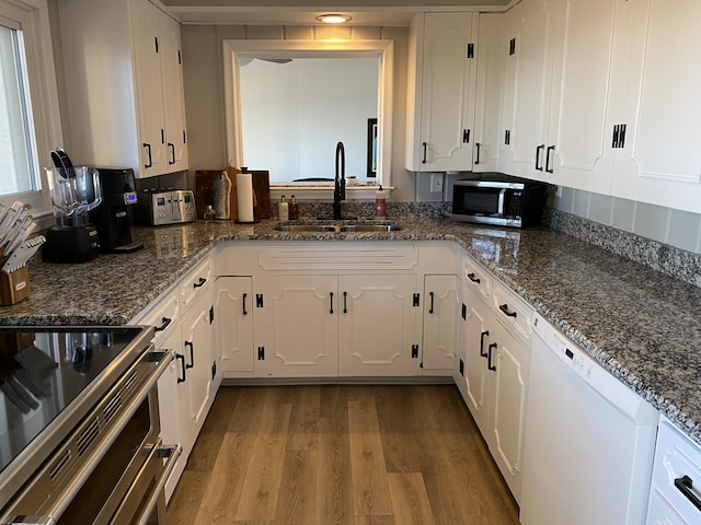 kitchen with a sink, stainless steel microwave, white cabinets, and white dishwasher