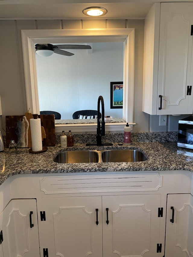 kitchen featuring a sink, dark stone counters, and white cabinets