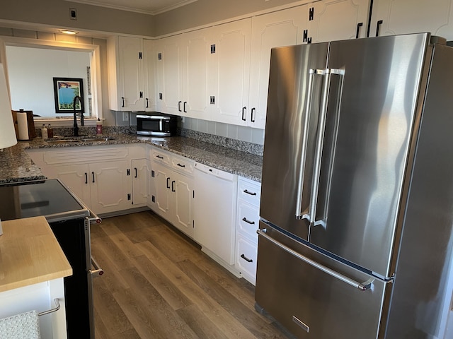 kitchen featuring dark wood-type flooring, a sink, dark stone counters, appliances with stainless steel finishes, and white cabinets