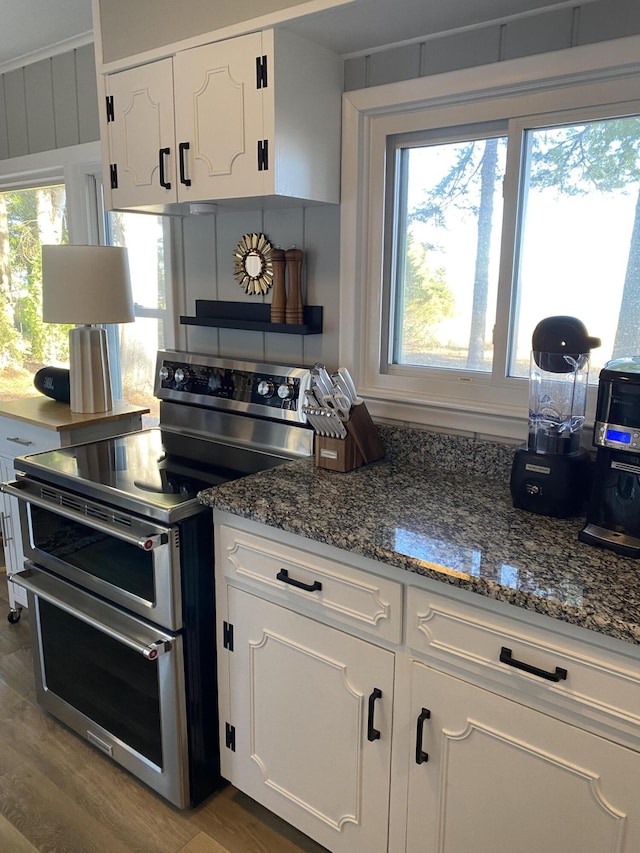 kitchen with wood finished floors, double oven range, plenty of natural light, and white cabinets