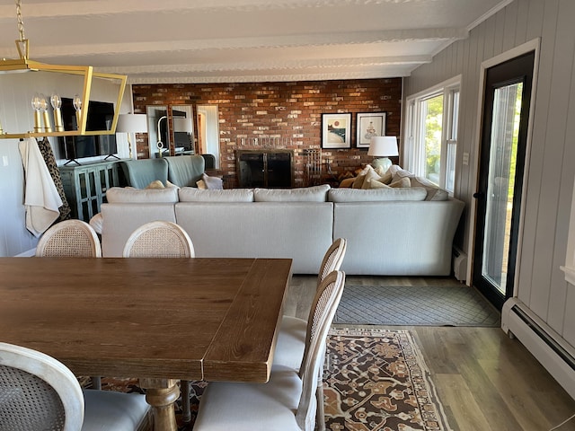 dining space featuring wood finished floors, brick wall, beam ceiling, wood walls, and baseboard heating