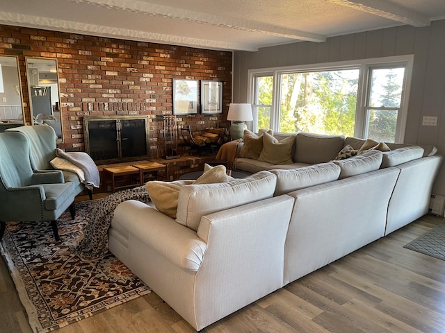 living room with beam ceiling, a baseboard radiator, a fireplace, and wood finished floors