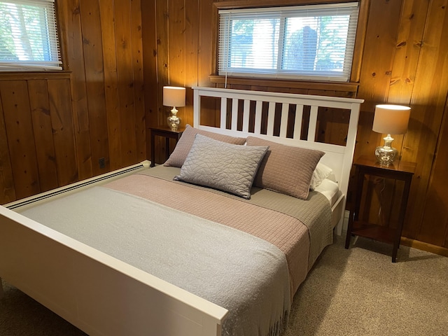 carpeted bedroom with baseboard heating and wooden walls