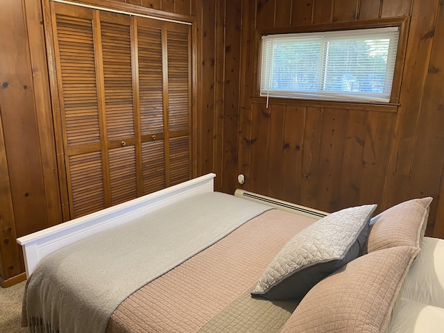 carpeted bedroom featuring wooden walls, a closet, and baseboard heating