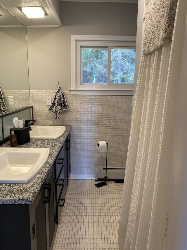 bathroom with tile patterned floors, baseboard heating, tile walls, and a sink