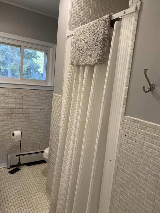 bathroom featuring wainscoting, a baseboard heating unit, tile walls, toilet, and tile patterned floors