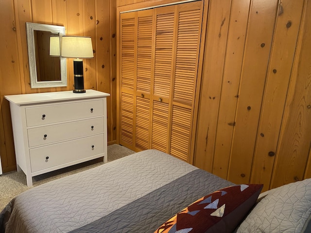 carpeted bedroom featuring a closet and wooden walls