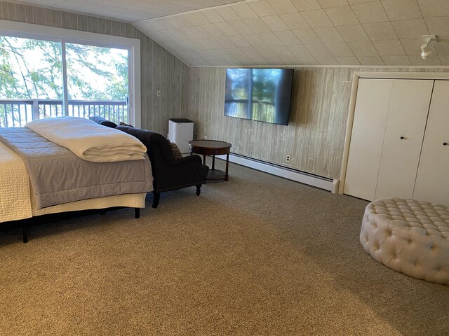 bedroom with a baseboard radiator, wood walls, carpet flooring, and vaulted ceiling