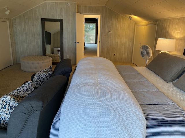 bedroom featuring a closet, carpet floors, wooden walls, and vaulted ceiling