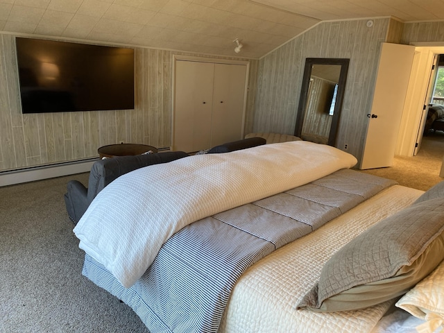 carpeted bedroom featuring a closet, a baseboard heating unit, and vaulted ceiling