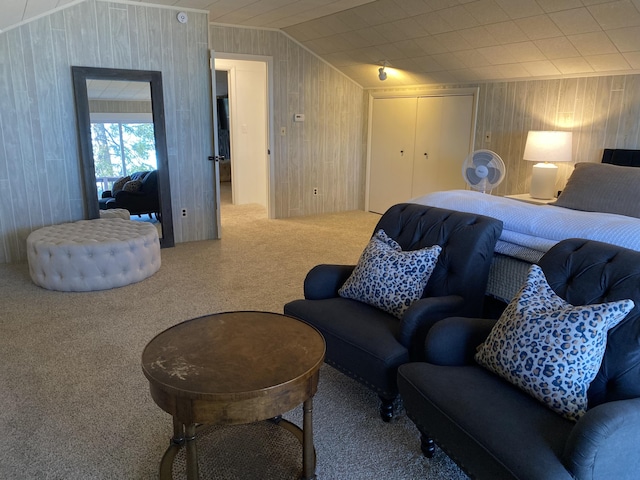 carpeted bedroom featuring a closet, lofted ceiling, and wood walls