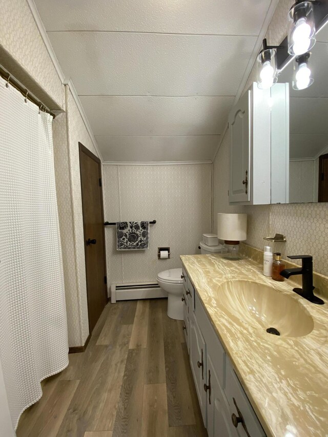 bathroom with wallpapered walls, vaulted ceiling, wood finished floors, and baseboard heating