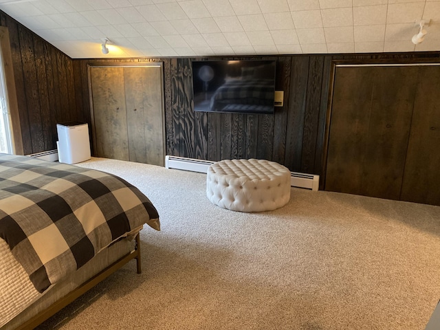 bedroom featuring wooden walls, carpet, and baseboard heating