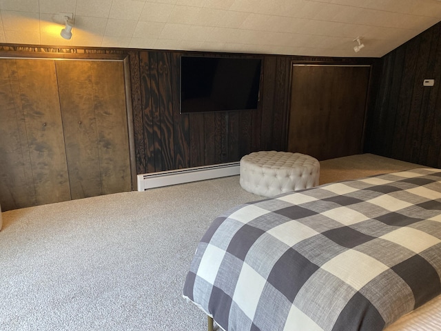 bedroom featuring a baseboard heating unit, carpet floors, and wood walls