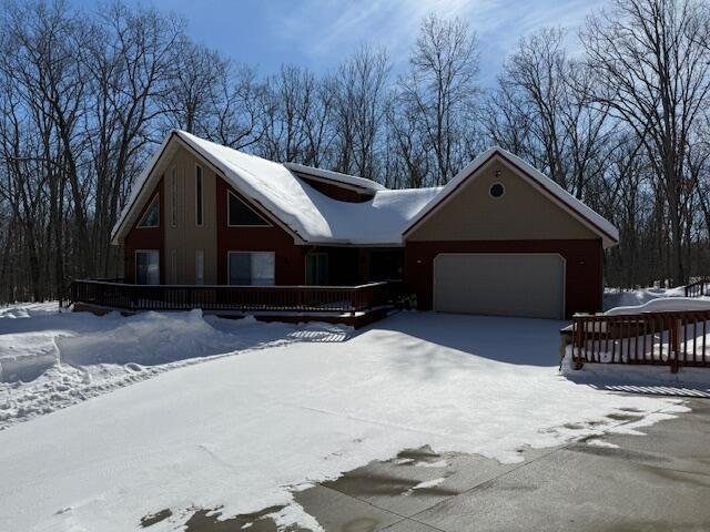 chalet / cabin with an attached garage, driveway, and a wooden deck