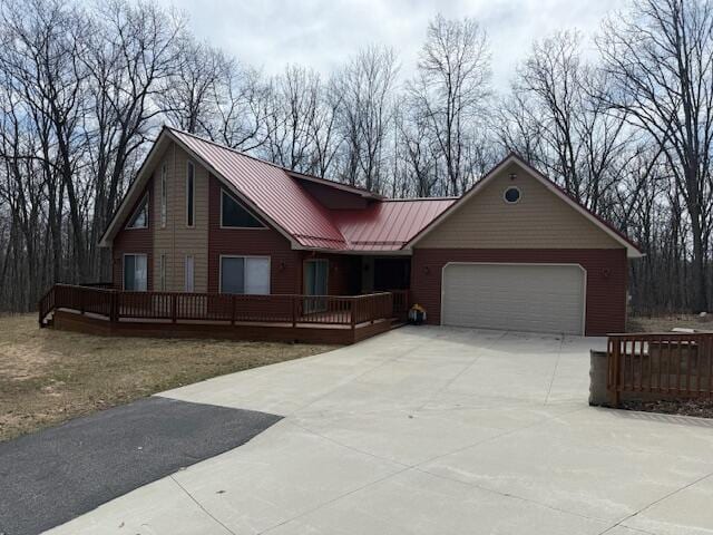 view of front of house featuring a deck, driveway, an attached garage, a standing seam roof, and metal roof