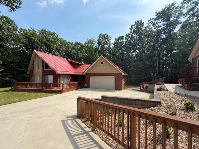 100 Innsbruck Ave, Roscommon, MI 48653 - view of front of home featuring driveway, an attached garage, and a metal roof