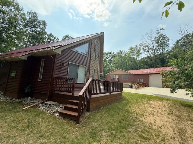 100 Innsbruck Ave, Roscommon, MI 48653 - rear view of house with a wooden deck, a metal roof, and a yard