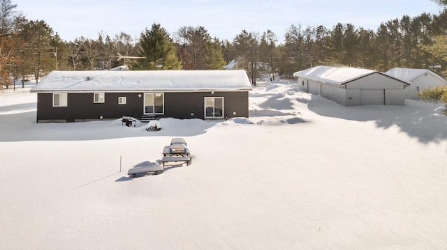 snow covered property featuring a detached garage