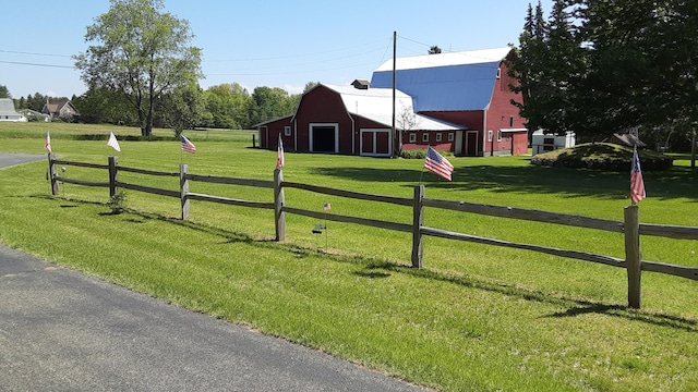 view of gate featuring a barn, fence, a lawn, and an outdoor structure