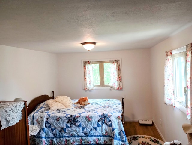 8110 Perry Rd, Houghton Lake, MI 48629 - bedroom featuring multiple windows, wood finished floors, baseboards, and a textured ceiling