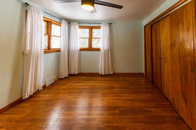 208 Stuckey Ave, Roscommon, MI 48653 - unfurnished bedroom with baseboards, ceiling fan, visible vents, a closet, and wood finished floors