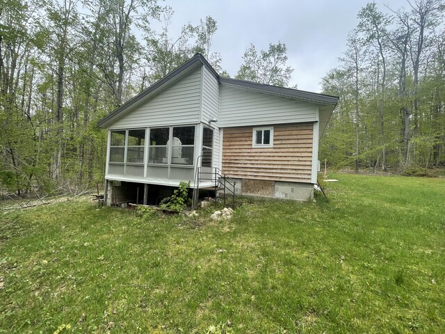 8598 N Sherman Rd, Frederic, MI 49733 - rear view of house with a lawn and a sunroom