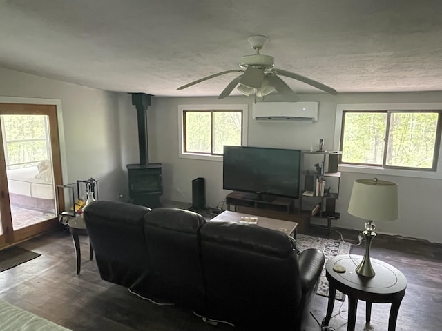 8598 N Sherman Rd, Frederic, MI 49733 - living room with a wall unit AC, a wood stove, dark wood finished floors, and ceiling fan