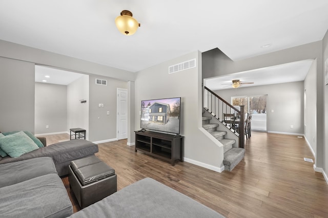 living area featuring stairway, visible vents, and wood finished floors