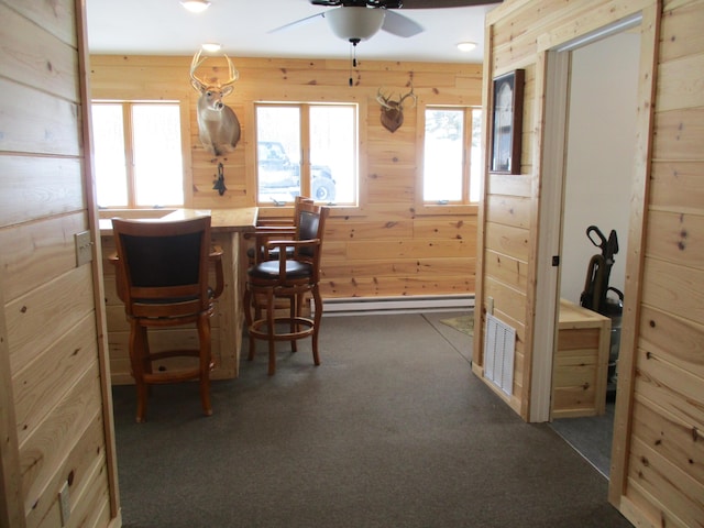 6876 Old Alba Rd, Gaylord, MI 49735 - dining area with ceiling fan, a baseboard heating unit, wood walls, and dark carpet