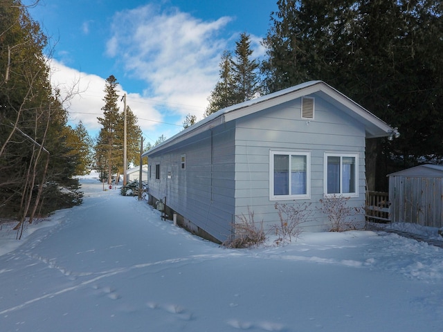 snow covered property featuring a storage unit and an outdoor structure