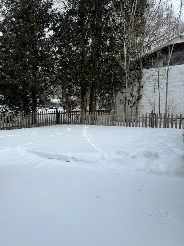 yard layered in snow featuring fence