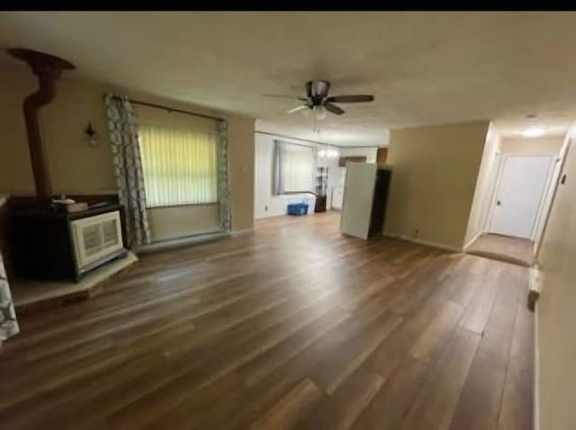 unfurnished living room with a wood stove, wood finished floors, and ceiling fan