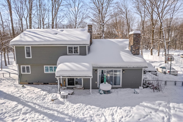 snow covered property with a chimney and fence