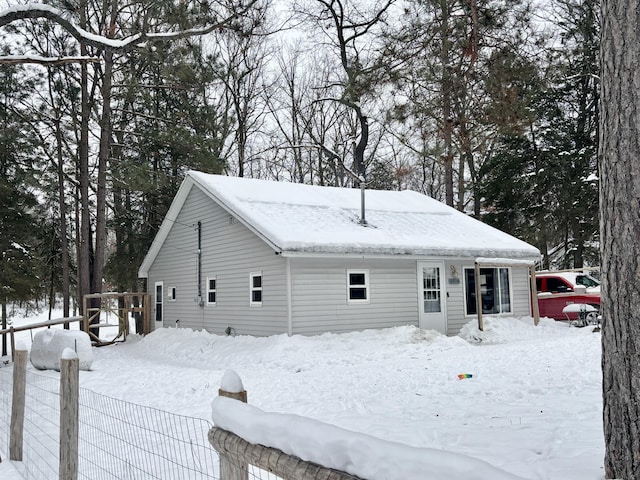 snow covered rear of property with fence