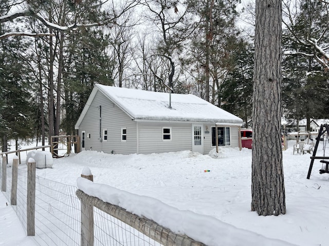 snow covered back of property featuring fence