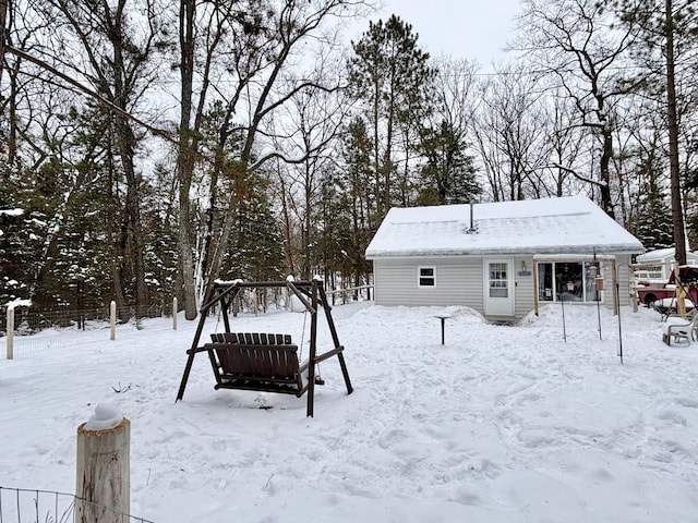 snow covered rear of property with an outdoor structure