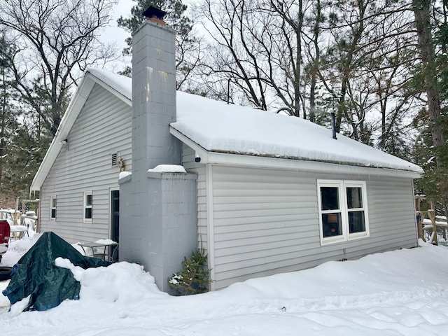 view of snow covered exterior with a chimney