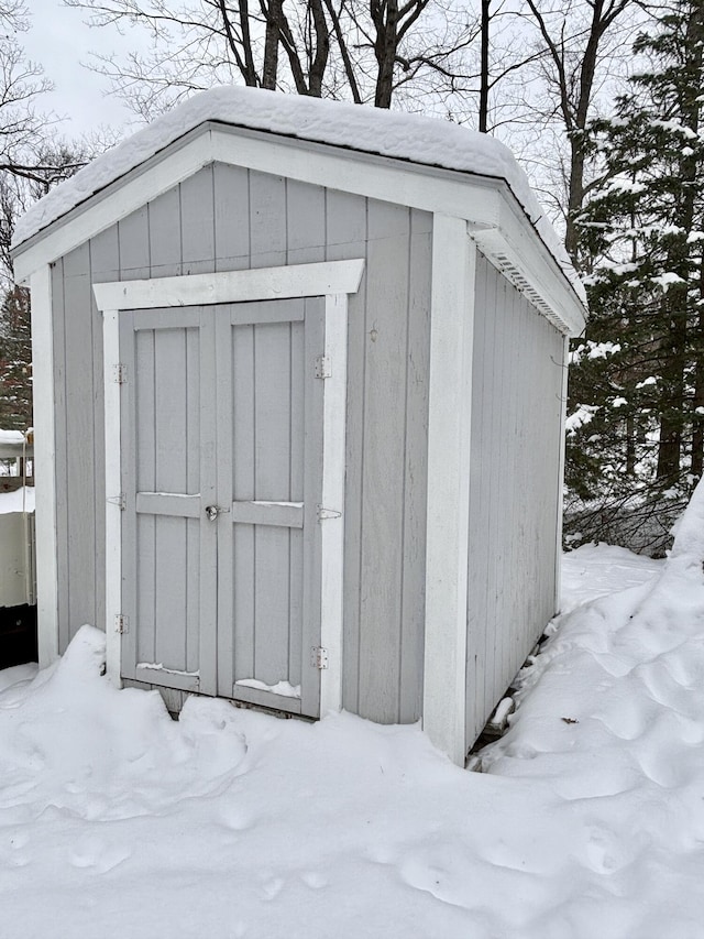 snow covered structure with an outbuilding and a shed