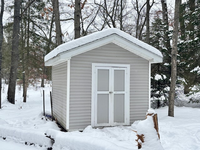 snow covered structure with an outdoor structure and a shed