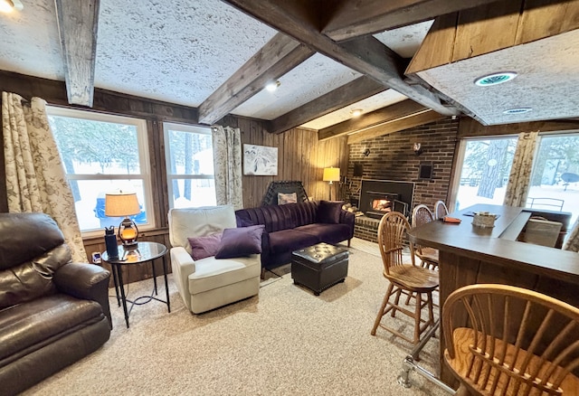 living room featuring a wealth of natural light, wooden walls, a brick fireplace, and carpet