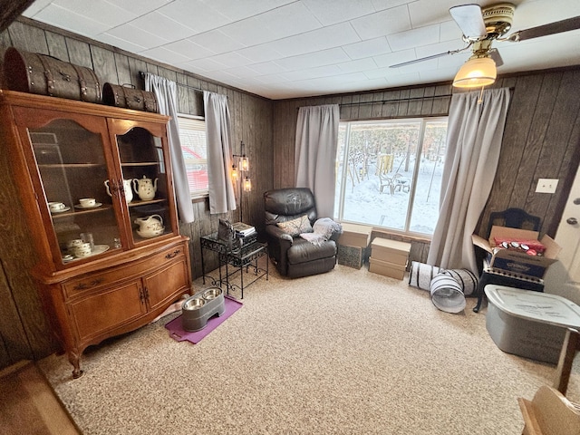 living area with carpet flooring, a healthy amount of sunlight, and wooden walls