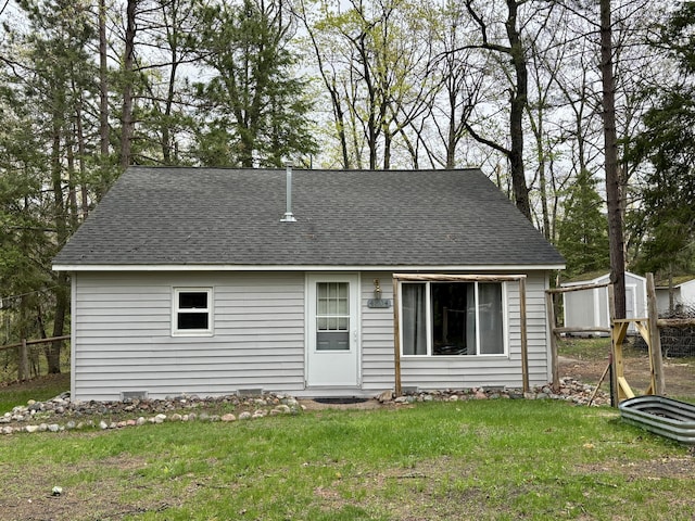 4804 Basil Dr, Comins, MI 48619 - view of front of home featuring roof with shingles, a storage unit, an outbuilding, and a front lawn