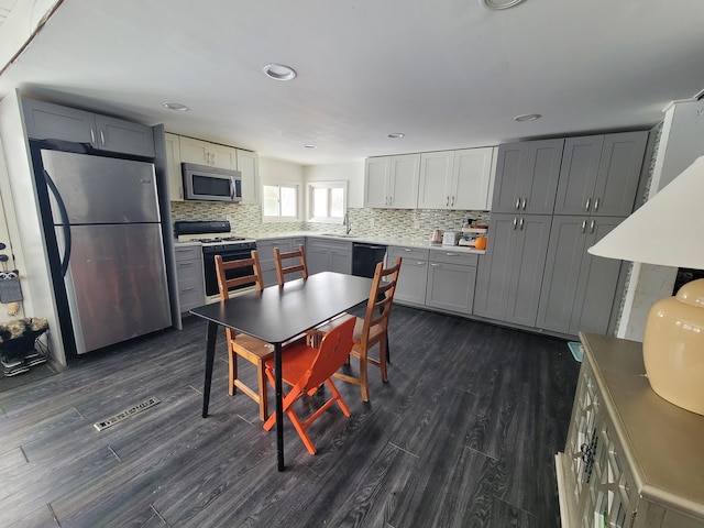 kitchen with stainless steel appliances, backsplash, visible vents, and dark wood finished floors