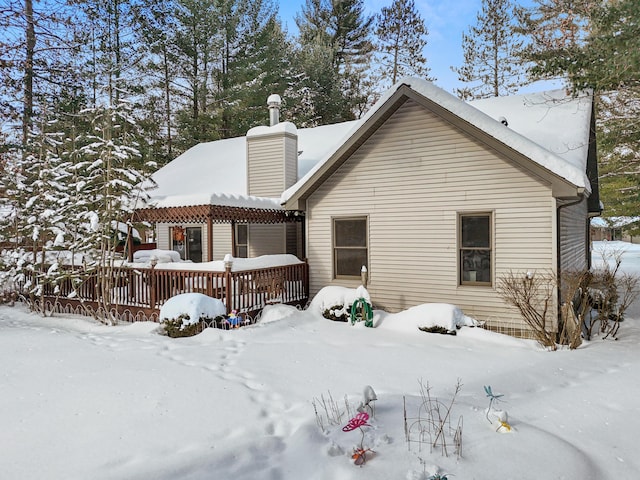 snow covered property featuring a deck and a chimney