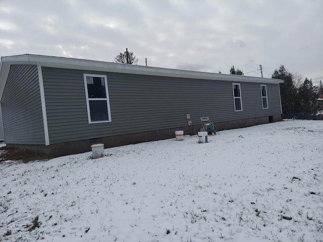 snow covered back of property featuring crawl space