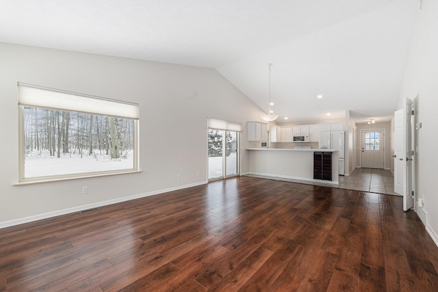 unfurnished living room with visible vents, baseboards, high vaulted ceiling, and dark wood-style floors