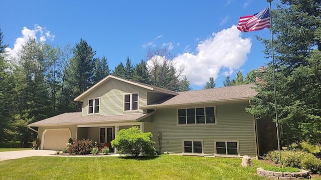 tri-level home featuring a garage, a chimney, concrete driveway, and a front lawn